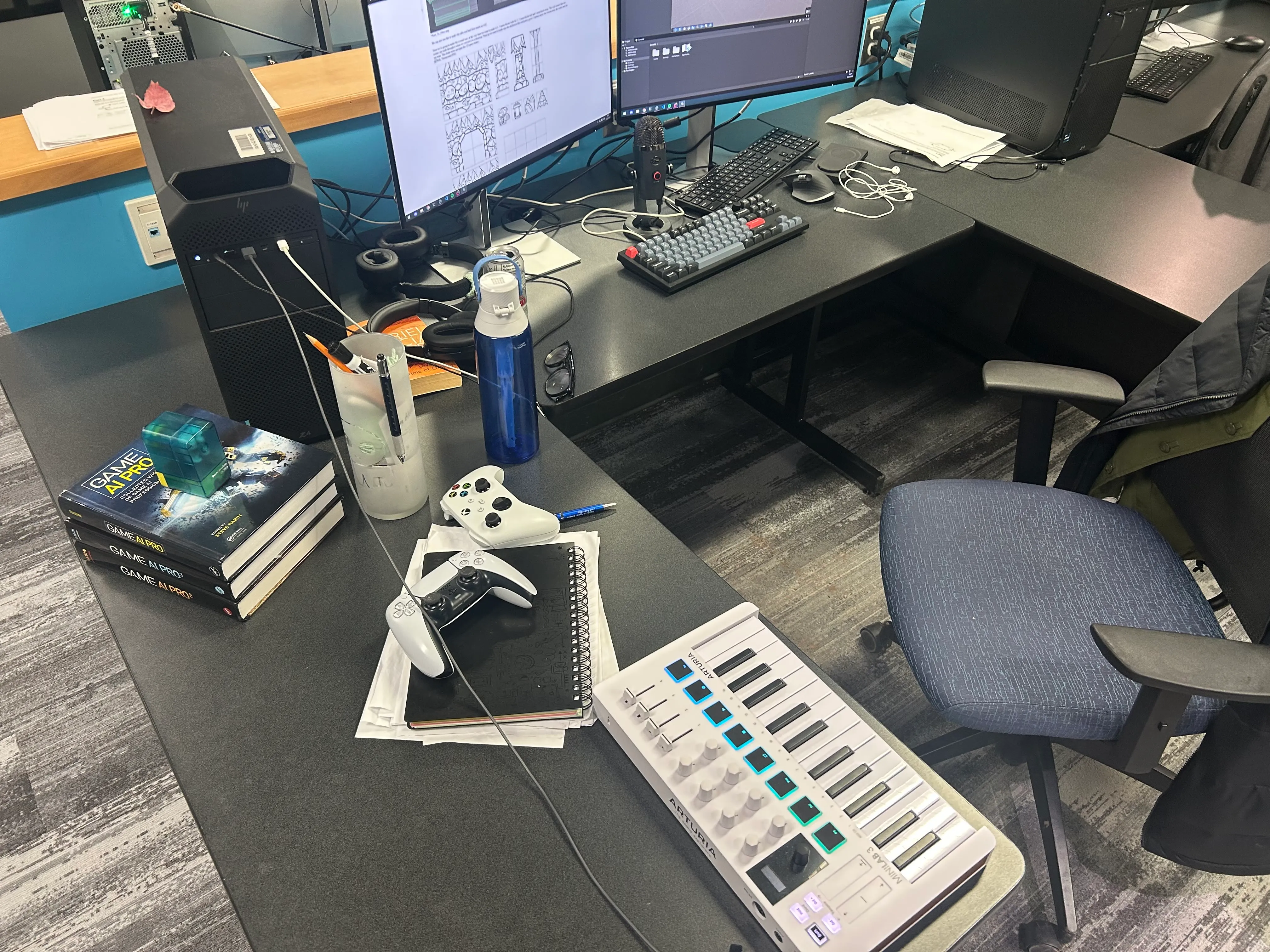 A workstation and desk setup, with two gamepads, a MIDI controller, the Game AI Pro textbooks, and a single maple leaf